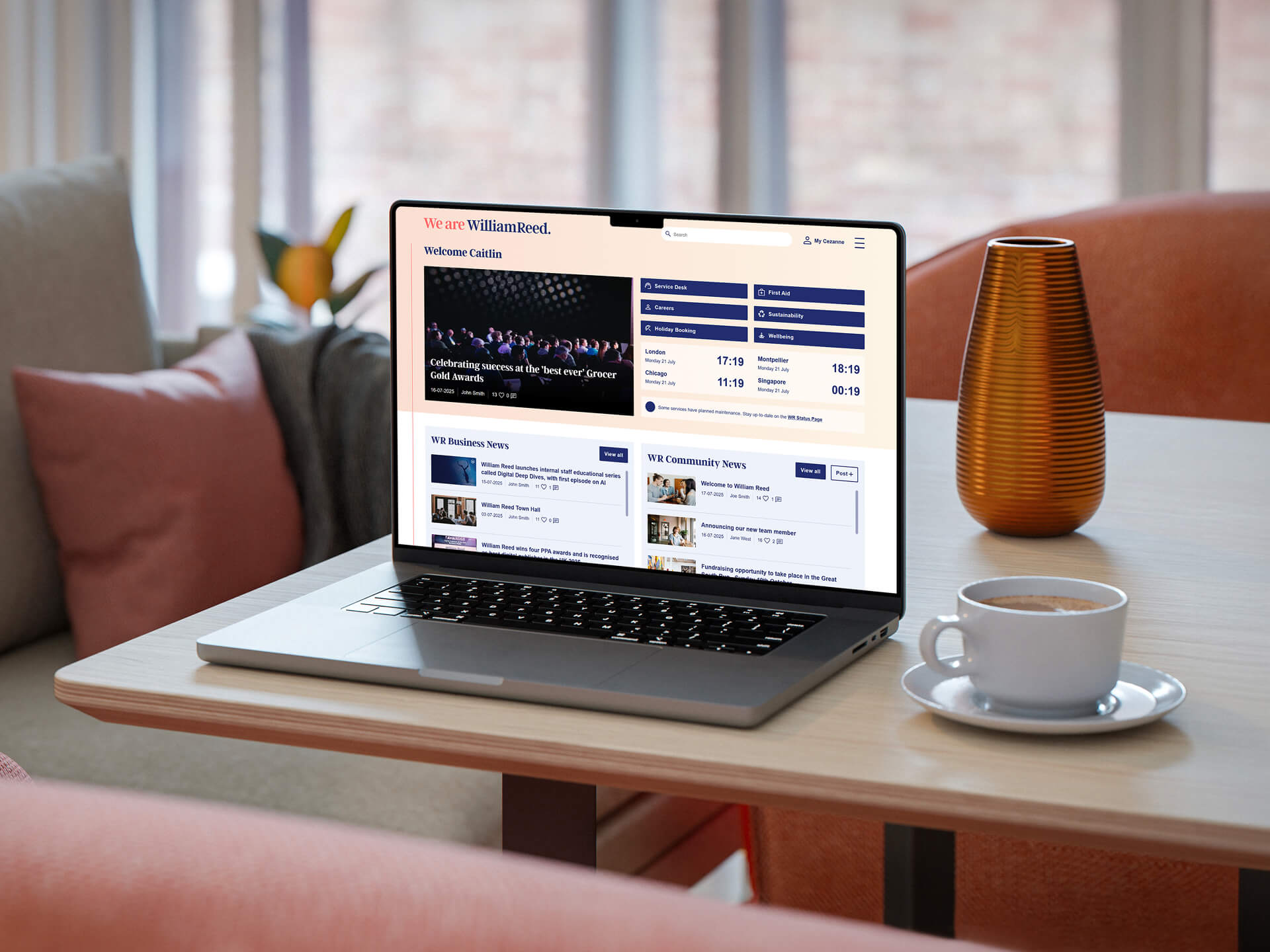An open laptop on a coffee table in a livingroom featuring the William Reed Intranet landing page