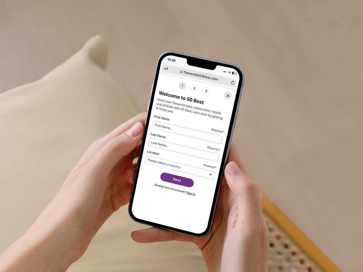 Someone holding a mobile phone with the sign-up screen for The World's 50 Best